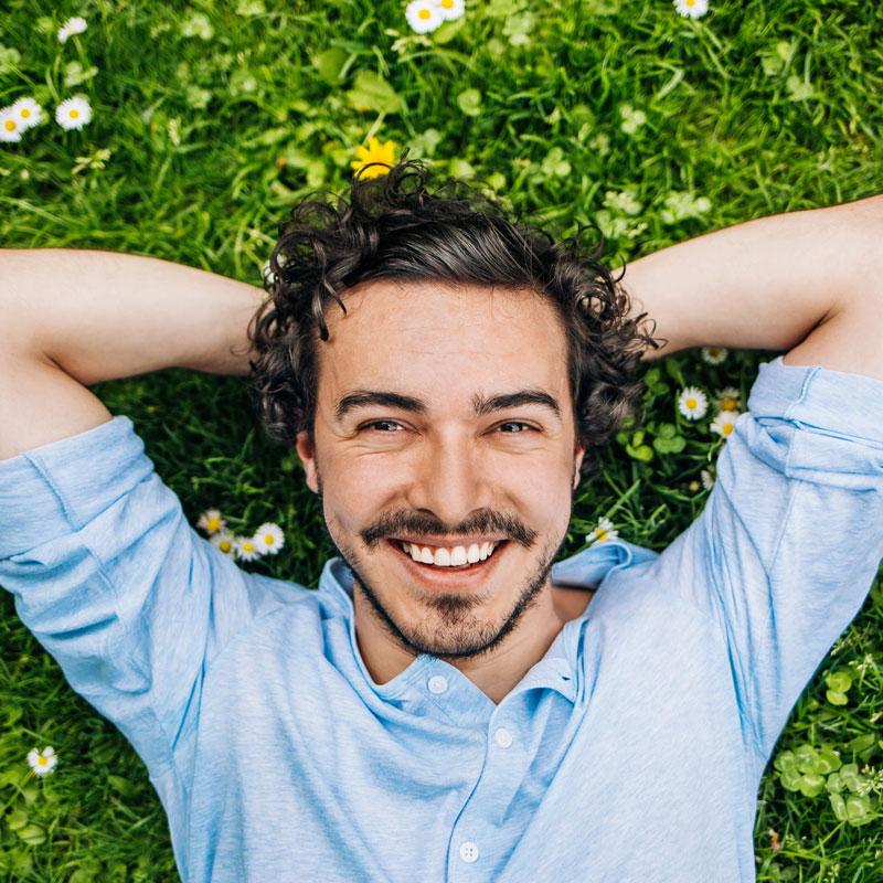 man laying in grass smiling
